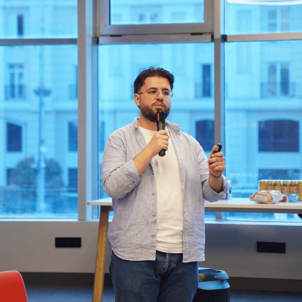 Metin speaking into a microphone at a community event
